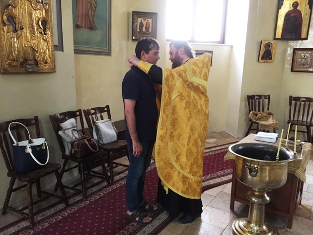 Отец Никон надевает крестик Олегу Васильеву